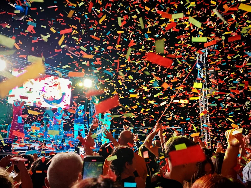 Crowd celebrating with colorful confetti at a concert.